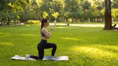 Parktaki bir kız spor için arka planda mavi bir spor paspasın üzerinde mor bir bluzla spor yapmaya gidiyor. Bir çayır ve ağaçlar.