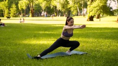 Parktaki bir kız spor için arka planda mavi bir spor paspasın üzerinde mor bir bluzla spor yapmaya gidiyor. Bir çayır ve ağaçlar.