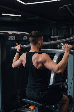 Adam spor salonundaki simülatörde sırtını sallıyor. koyu arkaplan