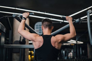 Adam spor salonundaki simülatörde sırtını sallıyor. koyu arkaplan