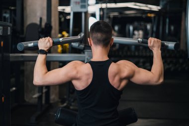 Adam spor salonundaki simülatörde sırtını sallıyor. koyu arkaplan