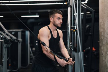 Adam göğsünü spor salonundaki simülatöre pompalıyor. koyu arkaplan