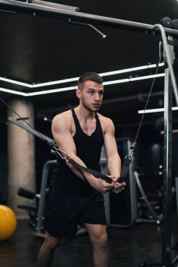 Adam göğsünü spor salonundaki simülatöre pompalıyor. koyu arkaplan