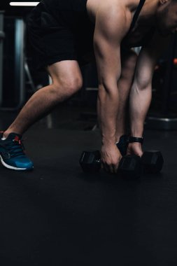 Adam spor salonunda dambılları kaldırıyor. koyu arkaplan