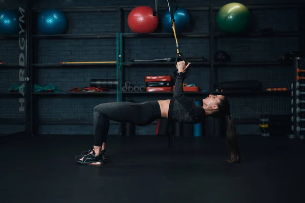 Kız sporcu spor salonunda trx egzersizi yapıyor. koyu arkaplan