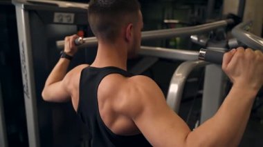 Adam spor salonundaki simülatörde sırtını sallıyor. koyu arkaplan