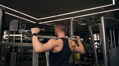 Adam spor salonundaki simülatörde sırtını sallıyor. koyu arkaplan