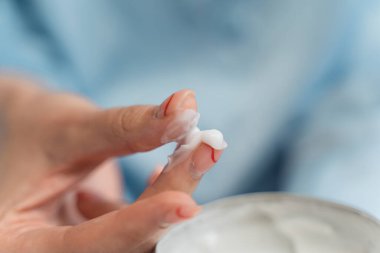 Mavi pijamalı beyaz krem tutan kız.