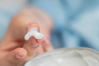 Kız kavanozdan beyaz kremayı yakın plan çekerek çıkarıyor.