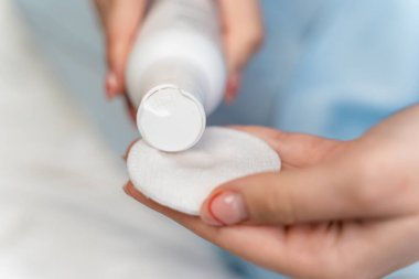 Kız pamuk yastığa losyon sürüyor. Yakından.