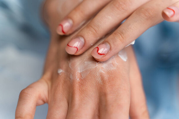 girl smears cream on her hand in blue pajamas