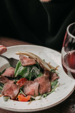 Biftek salatası yanında çatal ve şarap standı ile yenir.