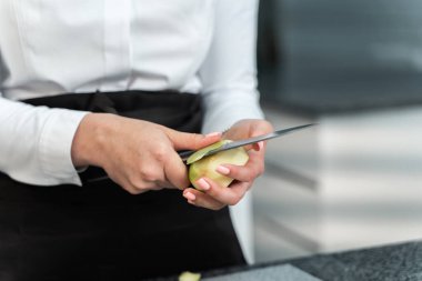 Kız elmayı bıçakla temizliyor.