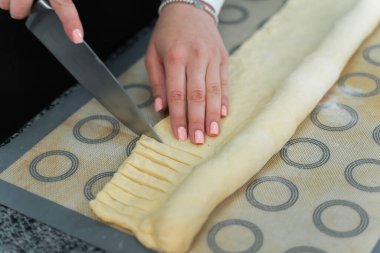 Şef hamuru bıçakla keser. Turta pişirir.