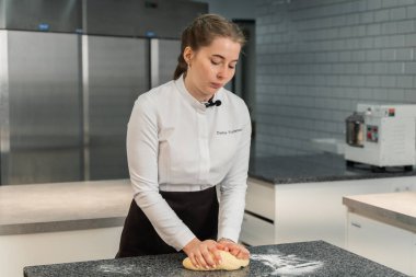 Kız hamuru masaya yuvarlıyor.