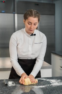 Kız hamuru masaya yuvarlıyor.