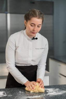 Kız hamuru masaya yuvarlıyor.