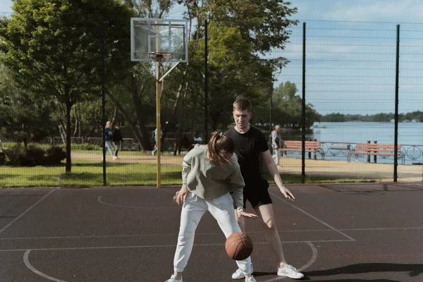 バスケットボールコートでバスケットボールをしている少女と少年は — ストック写真