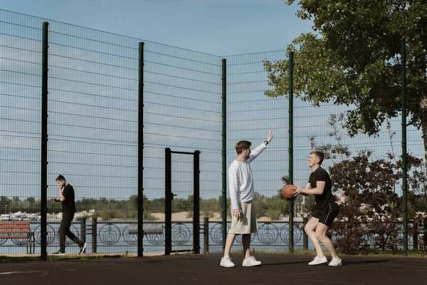Sahada iki adam basketbol oynuyor.