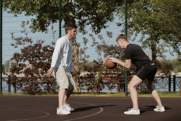 Sahada iki adam basketbol oynuyor.