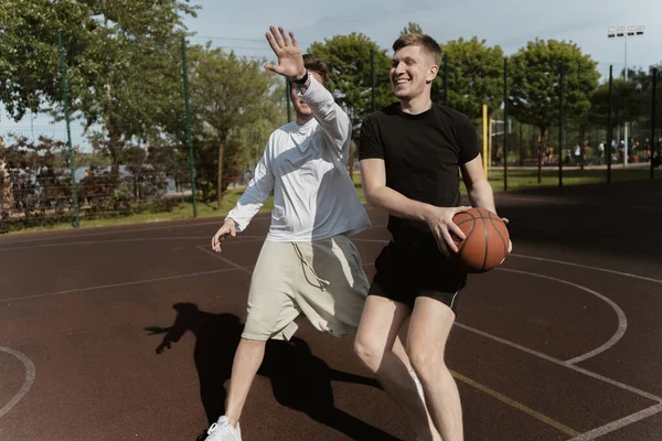 Sahada iki adam basketbol oynuyor.