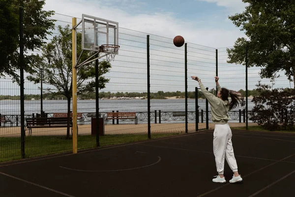 少女はバスケットボールコートのリングにボールを投げ込み — ストック写真