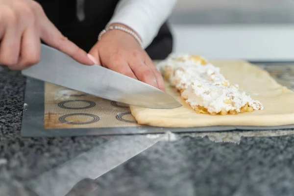 Bir kız pasta yapar ve hamuru bıçakla keser.