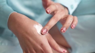 Kız mavi pijamalarıyla ellerine krem sürüyor.