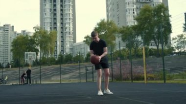 Adam basketbol sahasında topu ringe fırlatıyor.