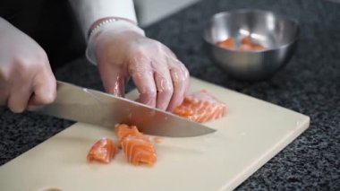 Şef mutfakta somon balığını bıçakla keser.
