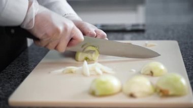 Kız mutfakta bıçakla soğan doğruyor.