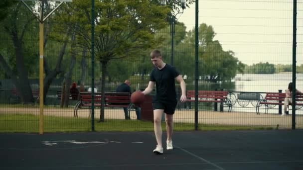 男はバスケットボールコートのリングにボールを投げ込み — ストック動画