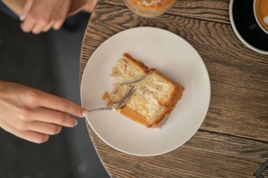 Tatlı bir kafede bir masada yatıyor ve çatalla yeniyor.
