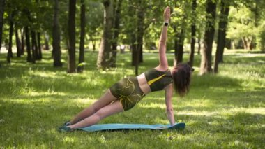 Genç bir kız spor için ormana / parka gider. # Yoga minderinde yeşil bir takım elbiseyle #