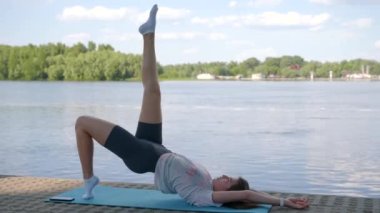 Genç bir kız yoga yapıyor. Akşamları nehrin kıyısında yoga minderinde.