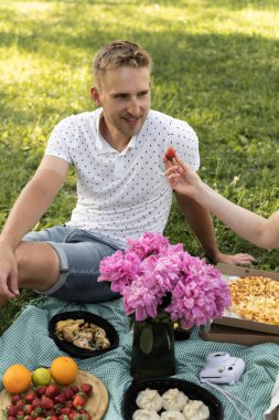 Tatilde piknikte bir adamla birlikte olan kız. Çilekli, güneşli, güneşli gün