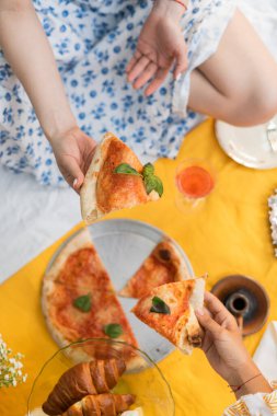 Mavi elbiseli bir kız tatilde parkta pizza tutuyor. Sarı elbise, mavi elbise