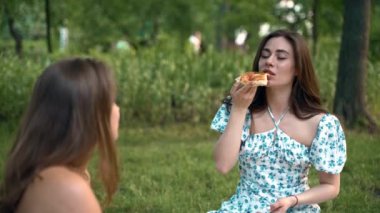 Mavi elbiseli bir kız tatilde parkta pizza yiyor. Sarı elbise, mavi elbise