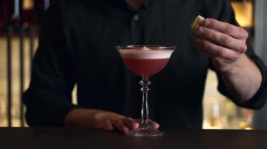 Barmen bir barda kokteyl hazırlıyor. Alkol ve şurup döker. Buz kullanır ve buzu kırar.
