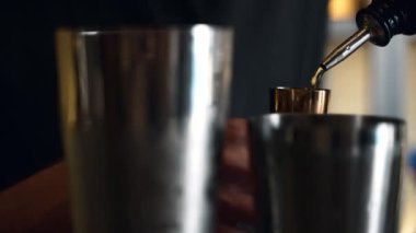 Barmen bir barda kokteyl hazırlıyor. Alkol ve şurup döker. Buz kullanır ve buzu kırar.