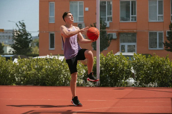 Genç adam basketbol sahasında basketbol oynuyor. Topu ringe fırlattı. Spor yapıyorum. sağlıklı vücut ve sağlıklı yaşam tarzı