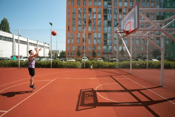 少年はバスケットボールコートでバスケットボールをしている ボールをリングに投げ込む スポーツをしてる 健康的な身体と健康的なライフスタイル — ストック写真