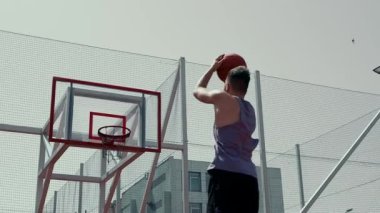 Genç adam basketbol sahasında basketbol oynuyor. Topu ringe fırlattı. Spor yapıyorum. sağlıklı vücut ve sağlıklı yaşam tarzı