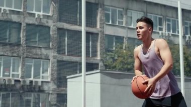 Genç adam basketbol sahasında basketbol oynuyor. Topu ringe fırlattı. Spor yapıyorum. sağlıklı vücut ve sağlıklı yaşam tarzı