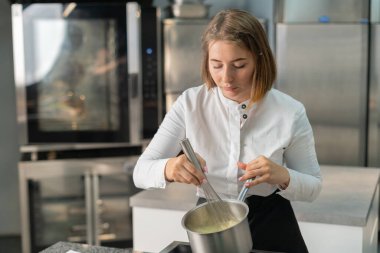 Genç aşçı kız tatlı yapıyor. Tatlı ve kek pişirir. Boşlukları doldurur ve meyveleri hazırlar. Pişirme, tatlı, tatlılar, karmaşık pişirme süreçleri.