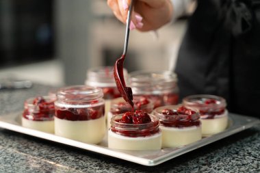 Genç aşçı kız tatlı yapıyor. Tatlı ve kek pişirir. Boşlukları doldurur ve meyveleri hazırlar. Pişirme, tatlı, tatlılar, karmaşık pişirme süreçleri.