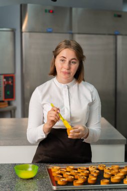 Genç aşçı kız tatlı yapıyor. Tatlı ve kek pişirir. Boşlukları doldurur ve meyveleri hazırlar. Pişirme, tatlı, tatlılar, karmaşık pişirme süreçleri.