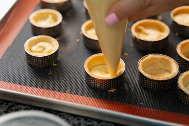 Genç aşçı kız tatlı yapıyor. Tatlı ve kek pişirir. Boşlukları doldurur ve meyveleri hazırlar. Pişirme, tatlı, tatlılar, karmaşık pişirme süreçleri.