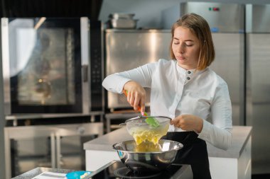 Genç aşçı kız tatlı yapıyor. Tatlı ve kek pişirir. Boşlukları doldurur ve meyveleri hazırlar. Pişirme, tatlı, tatlılar, karmaşık pişirme süreçleri.