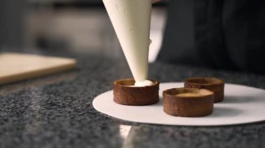 Genç aşçı kız tatlı yapıyor. Tatlı ve kek pişirir. Boşlukları doldurur ve meyveleri hazırlar. Pişirme, tatlı, tatlılar, karmaşık pişirme süreçleri.